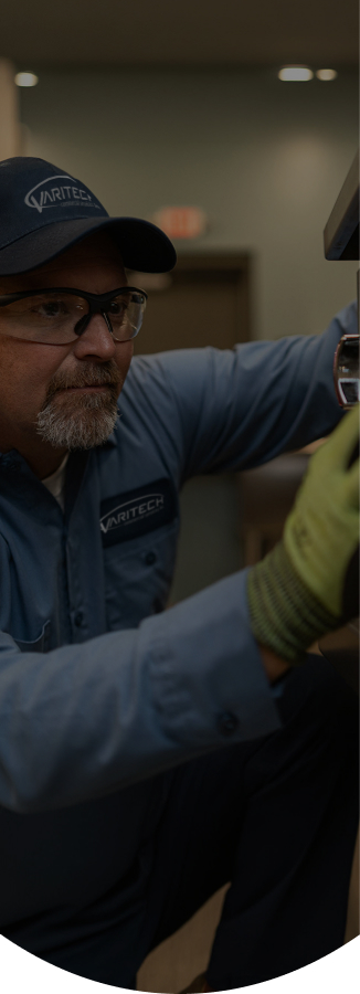 Service technician in a cap, safety glasses and work gloves repairing commercial kitchen equipment